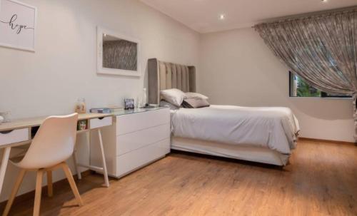 a bedroom with a bed and a desk and a desk at Mancave Luxury Homes in Alberton