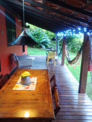a wooden porch with a table and a hammock at Suíte simples floresta verde in Angra dos Reis