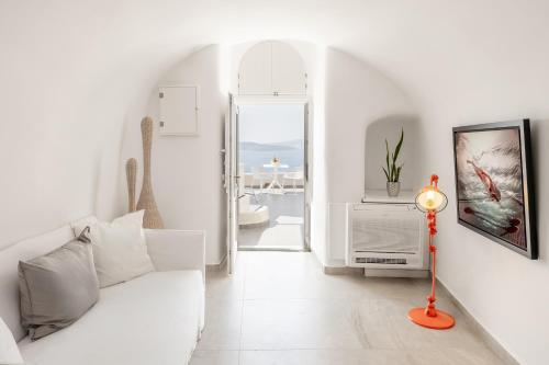 a white living room with a white couch and a lamp at Mancave Sanctum Caldera Suites in Oia