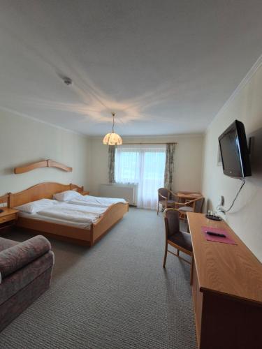 a hotel room with a bed and a tv at Hotel-Pension Asingerhof in Schladming