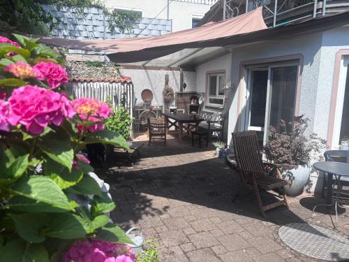 a patio with tables and chairs and pink flowers at Tor zum Bodensee in Stockach