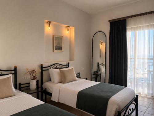 a hotel room with two beds and a window at Pansion Katerina in Ouranoupoli