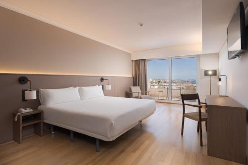 a hotel room with a bed and a desk and a window at B&B HOTEL Sado Setúbal in Setúbal