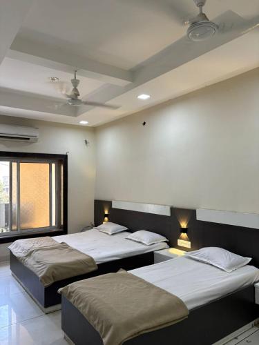 a room with three beds and a window at Sakkhar Palace in Indore