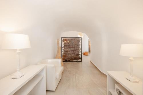 a living room with white walls and white furniture and two lamps at Mancave Sanctum Caldera Suites in Oia