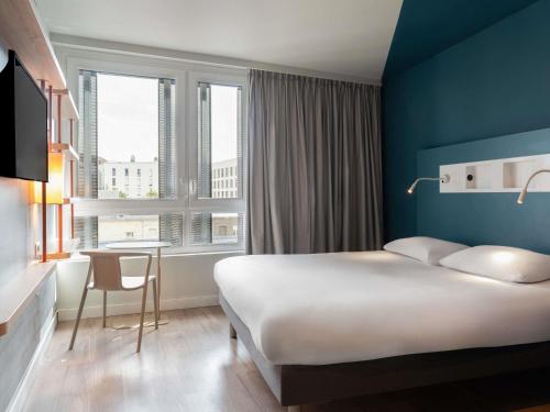 a hotel room with a bed and a desk and a window at ibis budget Rouen Centre Rive Gauche in Rouen