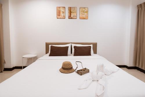 a white bed with a hat and a basket on it at JT Place Buriram in Buriram