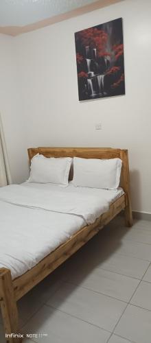 a wooden bed with white sheets and pillows on it at 1 bedroom BNB Meru in Meru