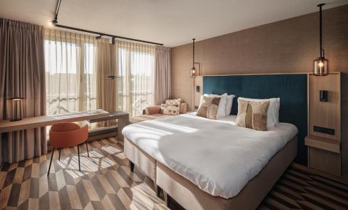 a hotel room with a large bed and a desk at Carlton Oasis Hotel in Spijkenisse