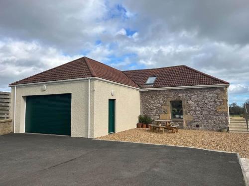 a detached house with a garage and a table at Converted Barn - Romantic Countryside Escape in Cupar