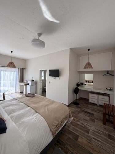 a bedroom with a large bed and a kitchen at Berg & Baai guesthouse in Plettenberg Bay