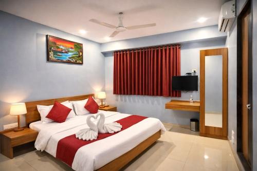 a bedroom with a bed with two white towels at Hotel Happinex Inn in Surat