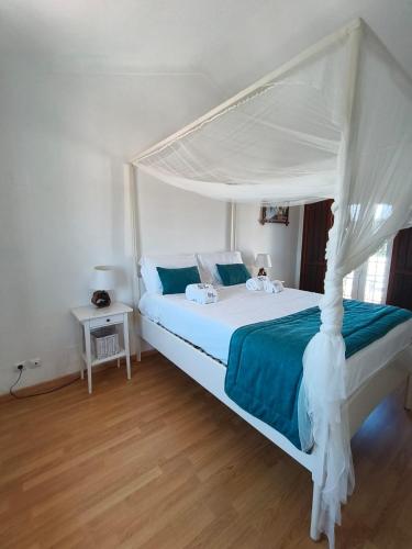 a bedroom with a white bed with a canopy at Refugio de São Luis in São Luis