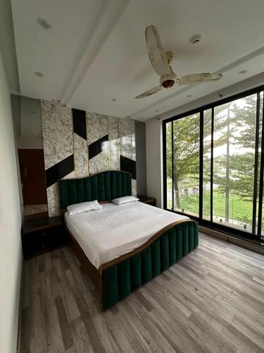 a bedroom with a large bed with a green headboard at Prestige Home in Lahore