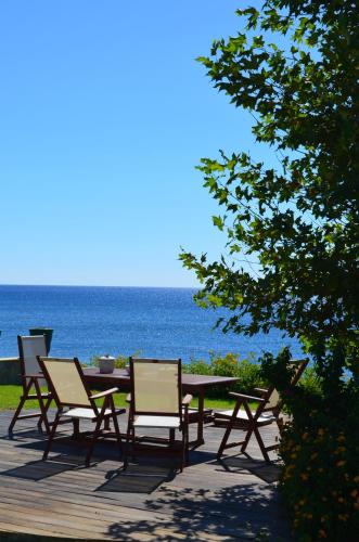 a wooden table and chairs with the ocean in the background at Private beach villa Princess in Kiotari