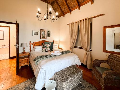 a bedroom with a bed and a chair and a chandelier at Far Niente Beachfront Guesthouse in Wilderness