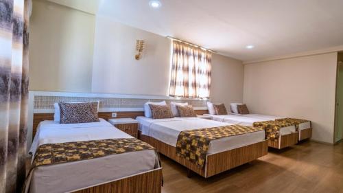 a room with three beds and a window at Grand Gülizar Otel in Urfa