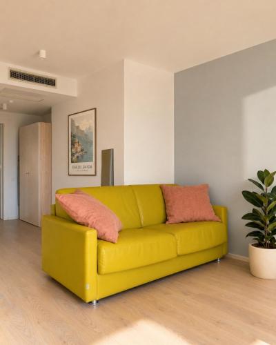 a yellow couch in a living room with a plant at View & Chill Apartment in Riva del Garda