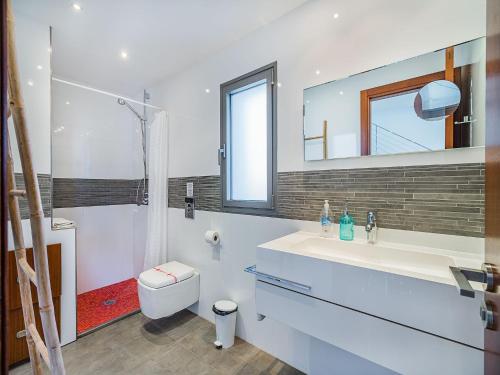 a bathroom with a sink and a toilet and a mirror at Playa de Muro Chalet with Pool for 6 in Playa de Muro