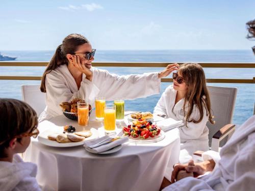 a group of people sitting at a table with food at Fairmont Monte Carlo in Monte Carlo