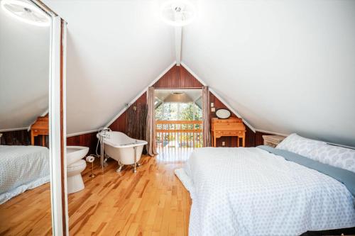 a attic bedroom with a bed and a tub and a sink at Spa & River - Chalet de la riviere Pauze in Chertsey
