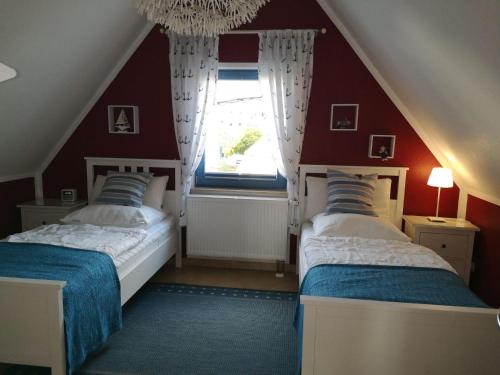 two beds in a room with red walls and a window at Ferienhaus-Seehund in Glowe