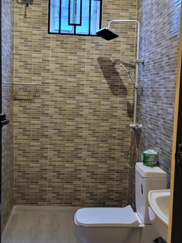 a bathroom with a shower with a toilet and a window at Matui House in Kinyasini