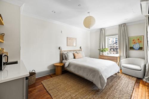 a white bedroom with a bed and a chair at Suite 5C at Maison Dupont a Dupont Circle Inn in Washington, D.C.