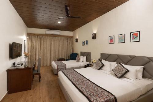 a hotel room with two beds and a desk at Manas Lifestyle Resort Igatpuri in Igatpuri