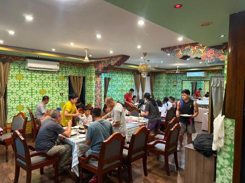 a group of people sitting at tables in a restaurant at Hotel Pelri in Phuntsholing