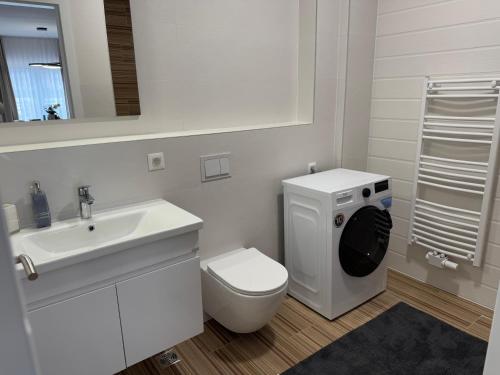 a white bathroom with a toilet and a sink at NOVA Olimpia Residence - Free Garage in Sarajevo