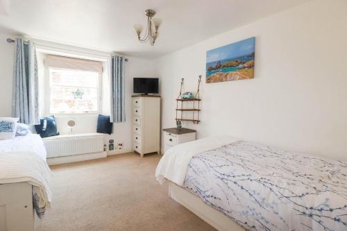 a white bedroom with a bed and a window at Stones Throw in St Austell