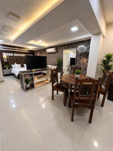 a living room with a table and chairs and a television at Megh hotel in Gangānagar