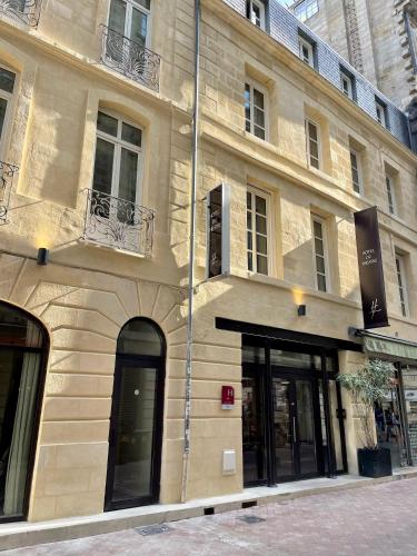 a building on a street with windows and doors at Hôtel du Théâtre - Hypercentre - Climatisé in Bordeaux