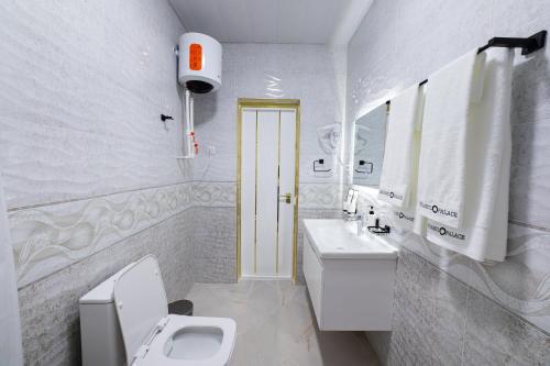 a white bathroom with a toilet and a sink at Istanbul Palace Hotel in Urganch