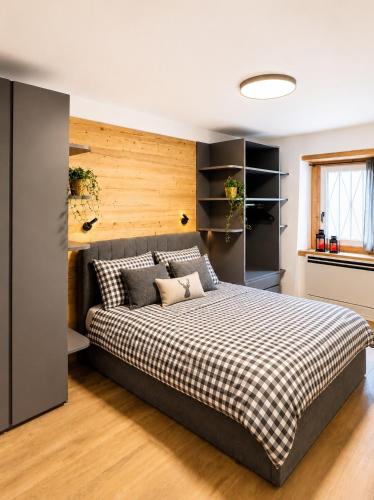 a bedroom with a large bed with a checkered blanket at Coriva Homes - Cogolo in Cogolo
