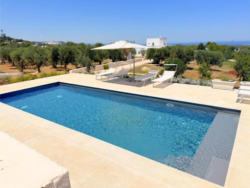 a swimming pool in a yard with chairs and an umbrella at Dimora Stune in Ostuni