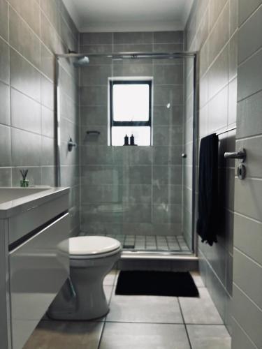 a bathroom with a shower and a toilet and a sink at Summer Set West in Somerset West