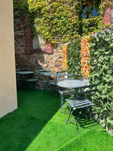 a patio with tables and chairs and a wall with flowers at Le Nuage - Vidéoprojecteur - Terrasse - 5min Gare in Ploumagoar