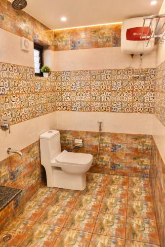 a bathroom with a toilet and tiles on the wall at The Oak Lake Cottage Boho in Nainital