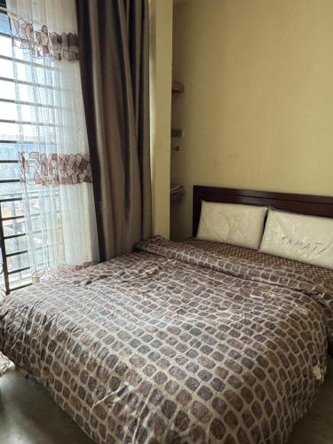 a bed in a bedroom with a large window at Cozy home with a generator and Wi-Fi in Kinshasa
