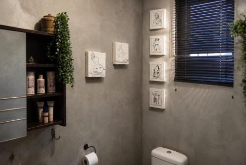 a bathroom with a toilet and pictures on the wall at Gadute Haven - Luxury Apartment in Pretoria