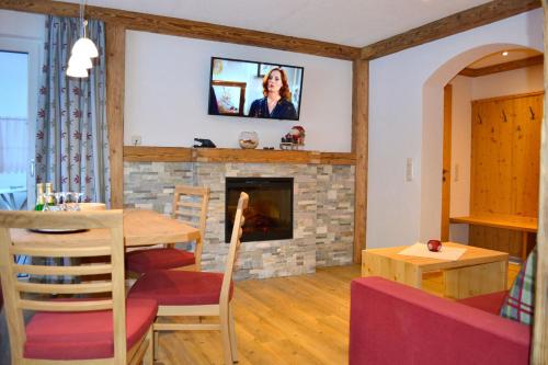 salon ze stołem i kominkiem w obiekcie Pension Alpenperle w mieście Holzgau