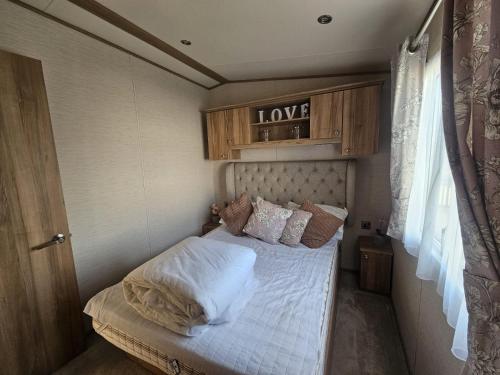 a small bedroom with a bed with white sheets and pillows at A21 Unity Beach, Brean in Brean