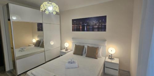 a white bedroom with two beds and two lamps at Sun Sea 3 sea view in Shkorpilovtsi