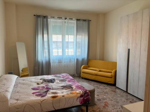 a bedroom with a bed and a couch and a window at Nicole's House in Asti