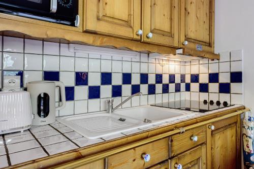 a kitchen with a sink and blue and white tiles at Les Ancolies Benelli in Les Menuires