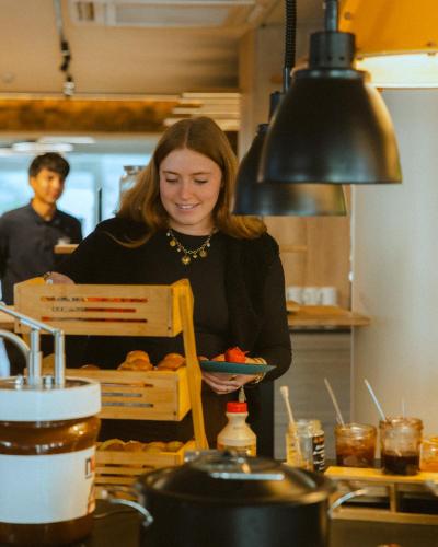 a woman standing in a kitchen holding a plate of food at Urban Hotel & Spa Aix-les-Bains - BW Signature Collection in Aix-les-Bains