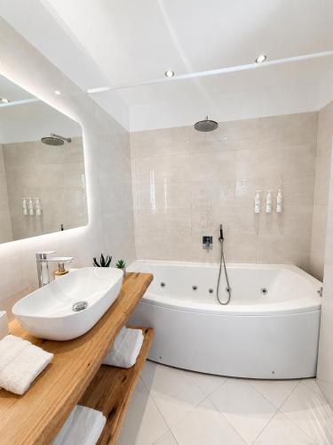 a white bathroom with a tub and a sink at Patmos Sunshine Houses - Quiet Stay, 5-min Walk to Skala Square in Patmos