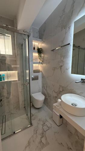 a bathroom with a shower and a toilet and a sink at Loutraki Sea Breeze Sunset Apt in Loutraki